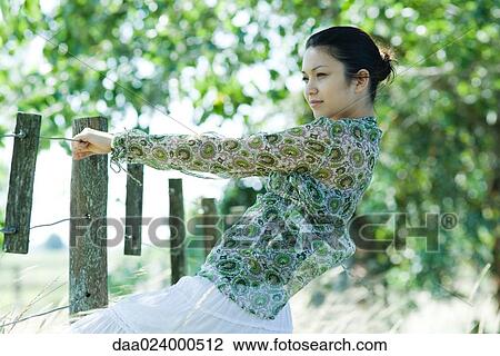 Young woman holding on to rural fence, leaning back View Large Photo Image Stock Image - Young woman holding on to rural fence, leaning back. Fotosearch