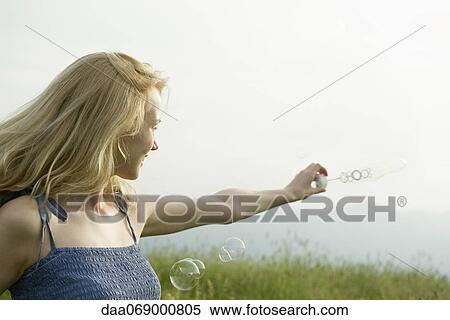 Young woman holding out bubble wand in wind View Large Photo Image Stock Photography - Young woman holding out bubble wand in wind. Fotosearch