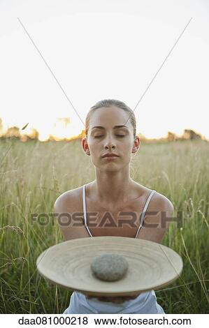 Young woman holding out plate with stone, eyes closed View Large Photo Image Stock Photo - Young woman holding out plate with stone, eyes closed. Fotosearch