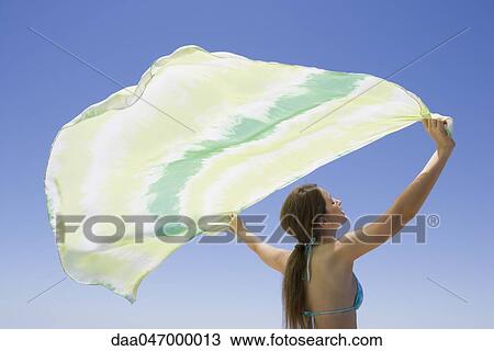 Young woman holding scarf in breeze View Large Photo Image Stock Image - Young woman holding scarf in breeze. Fotosearch