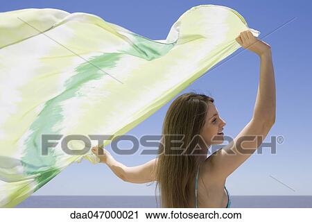 Young woman holding scarf in breeze View Large Photo Image Stock Image - Young woman holding scarf in breeze. Fotosearch
