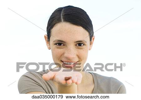 Stock Photo - Young woman holding single brown seed in palm of hand extended to camera. Fotosearch