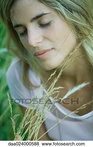 Young woman holding tall grass, eyes closed, close-up View Large Photo Image Stock Photo - Young woman holding tall grass, eyes closed, close-up. Fotosearch