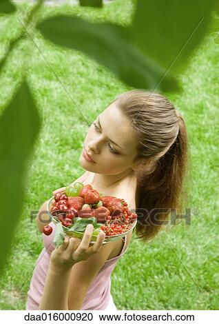 Young woman holding up bowl of fruit View Large Photo Image Stock Image - Young woman holding up bowl of fruit. Fotosearch