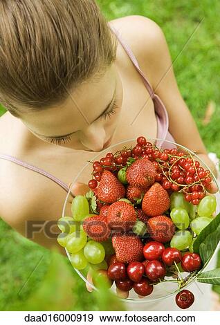 Young woman holding up bowl of fruit View Large Photo Image Stock Photo - Young woman holding up bowl of fruit. Fotosearch
