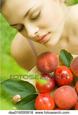 Young woman holding up bowl of peaches and nectarines View Large Photo Image Stock Photo - Young woman holding up bowl of peaches and nectarines. Fotosearch