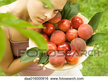 Young woman holding up bowl of peaches and nectarines View Large Photo Image Stock Photograph - Young woman holding up bowl of peaches and nectarines. Fotosearch