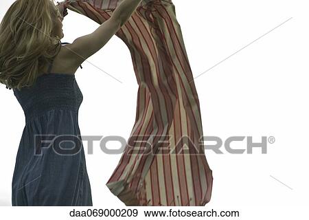 Stock Photo - Young woman holding up picnic blanket in breeze. Fotosearch