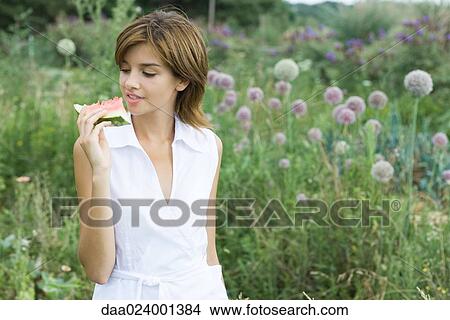 Young woman holding up slice of watermelon View Large Photo Image Picture - Young woman holding up slice of watermelon. Fotosearch