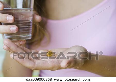 Young woman holding vitamin pill and glass of water, cropped View Large Photo Image Stock Photo - Young woman holding vitamin pill and glass of water, cropped. Fotosearch