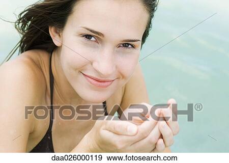 Young woman holding water in cupped hands, smiling at camera, close-up View Large Photo Image Stock Photo - Young woman holding water in cupped hands, smiling at camera, close-up. Fotosearch