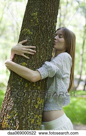 Stock Image - Young woman hugging and kissing tree. Fotosearch