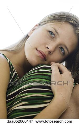 Stock Photo - Young woman hugging knees, contemplatively looking away, portrait. Fotosearch