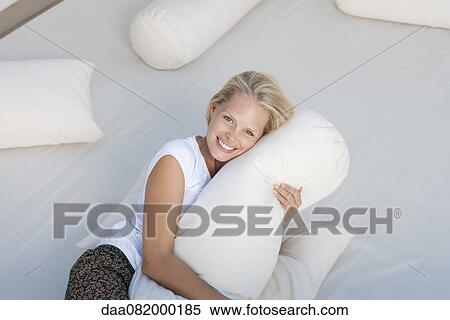 Stock Photography - Young woman hugging pillow on bed. Fotosearch