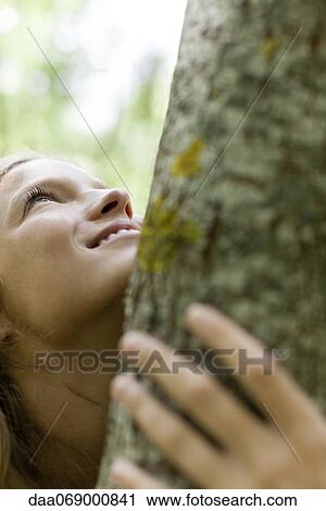 Stock Image - Young woman hugging tree, cropped. Fotosearch