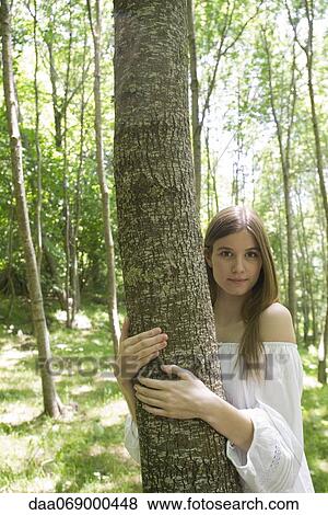 Stock Photo - Young woman hugging tree, portrait. Fotosearch