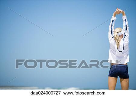 Young woman in active wear stretching on beach, rear view View Large Photo Image Stock Photo - Young woman in active wear stretching on beach, rear view. Fotosearch