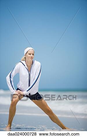Young woman in active wear, stretching on beach View Large Photo Image Stock Photo - Young woman in active wear, stretching on beach. Fotosearch