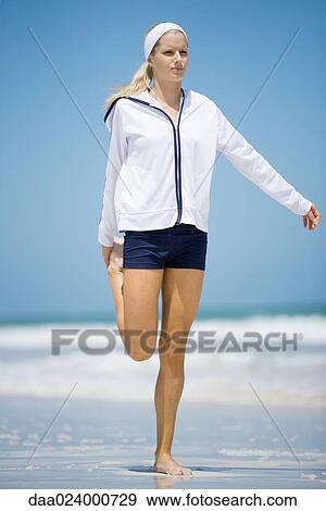 Young woman in active wear, stretching on beach View Large Photo Image Stock Photo - Young woman in active wear, stretching on beach. Fotosearch
