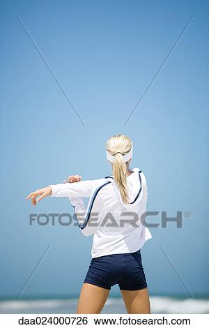 Young woman in active wear stretching on beach, rear view View Large Photo Image Stock Photograph - Young woman in active wear stretching on beach, rear view. Fotosearch
