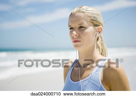 Young woman in active wear wearing earphones on beach, head and shoulders View Large Photo Image Stock Image - Young woman in active wear wearing earphones on beach, head and shoulders. Fotosearch