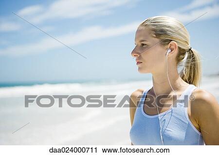 Young woman in active wear wearing earphones on beach, head and shoulders View Large Photo Image Stock Image - Young woman in active wear wearing earphones on beach, head and shoulders. Fotosearch