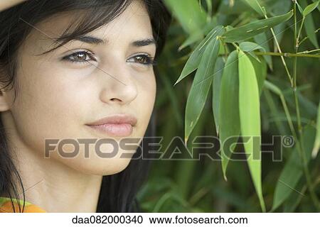 Stock Image - Young woman in bamboo foliage, portrait. Fotosearch