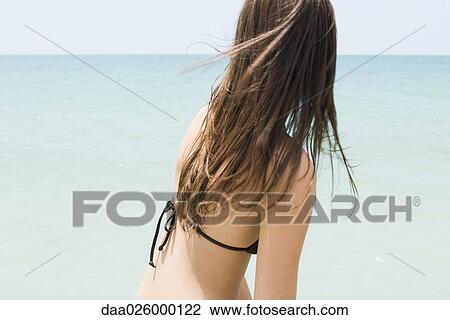 Young woman in bikini at the beach, looking at horizon, side view View Large Photo Image Stock Image - Young woman in bikini at the beach, looking at horizon, side view. Fotosearch
