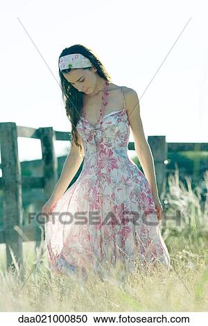 Young woman in dress walking through field View Large Photo Image Stock Image - Young woman in dress walking through field. Fotosearch