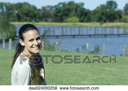 Young woman in park, smiling at camera View Large Photo Image Stock Photo - Young woman in park, smiling at camera. Fotosearch