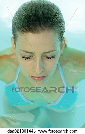 Stock Photography - Young woman in pool, eyes closed, high angle view. Fotosearch