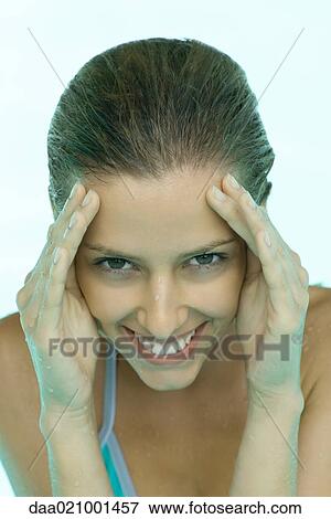 Stock Photo - Young woman in pool, hands on side of face. Fotosearch