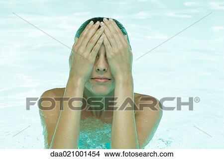 Picture - Young woman in pool, wiping face. Fotosearch