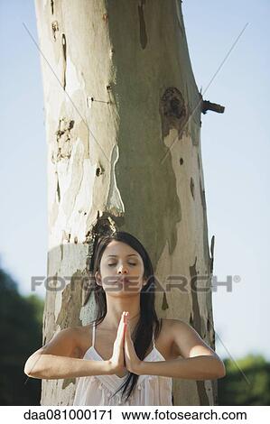 Stock Image - Young woman in prayer position outdoors. Fotosearch