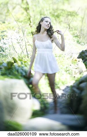 Young woman in slip standing outdoors, holding lock of hair, looking away View Large Photo Image Stock Photo - Young woman in slip standing outdoors, holding lock of hair, looking away. Fotosearch