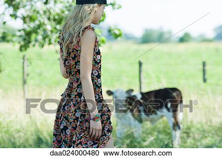 Young woman in sundress walking toward cow, side view View Large Photo Image Stock Image - Young woman in sundress walking toward cow, side view. Fotosearch