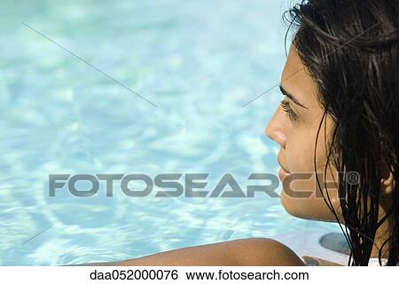 Young woman in swimming pool, looking away in thought View Large Photo Image Stock Photograph - Young woman in swimming pool, looking away in thought. Fotosearch