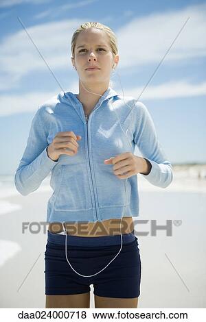 Young woman jogging on beach, listening to MP3 player View Large Photo Image Stock Photo - Young woman jogging on beach, listening to MP3 player. Fotosearch