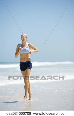 Stock Photo - Young woman jogging on beach. Fotosearch