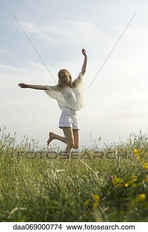 Young woman jumping in meadow View Large Photo Image Picture - Young woman jumping in meadow. Fotosearch