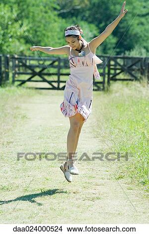 Picture - Young woman jumping in rural setting. Fotosearch