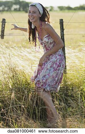 Stock Image - Young woman laughing in field. Fotosearch