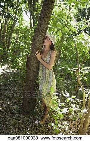 Young woman leaning against tree in woods View Large Photo Image Stock Photo - Young woman leaning against tree in woods. Fotosearch