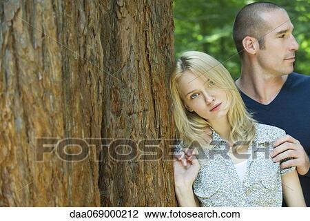 Young woman leaning against tree trunk View Large Photo Image Stock Image - Young woman leaning against tree trunk. Fotosearch
