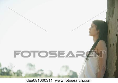 Young woman leaning aginst tree trunk, side view View Large Photo Image Stock Image - Young woman leaning aginst tree trunk, side view. Fotosearch