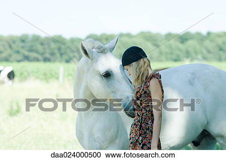 Young woman leaning her head against horse View Large Photo Image Stock Image - Young woman leaning her head against horse. Fotosearch