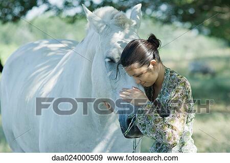 Young woman leaning her head against horse View Large Photo Image Stock Photo - Young woman leaning her head against horse. Fotosearch