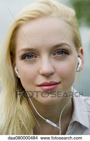 Picture - Young woman listening to earphones, portrait. Fotosearch