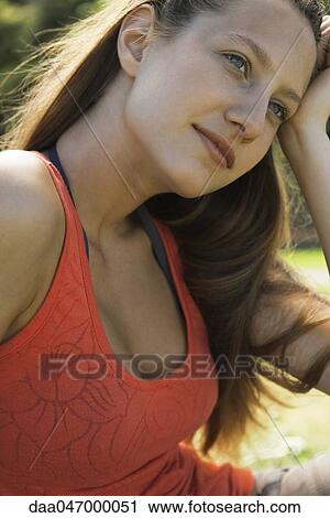 Stock Image - Young woman looking away dreamily, portrait. Fotosearch