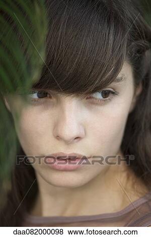 Stock Photo - Young woman looking away in thought, portrait. Fotosearch